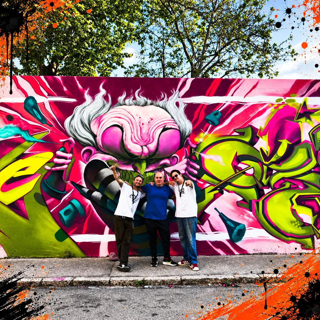Grupo de personas posando delante de un mural de graffiti terminado