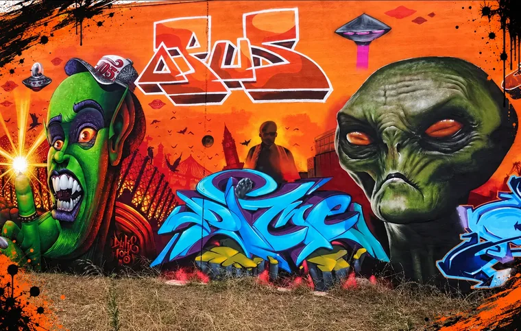 Mural exterior de graffiti con personajes y lettering de colores